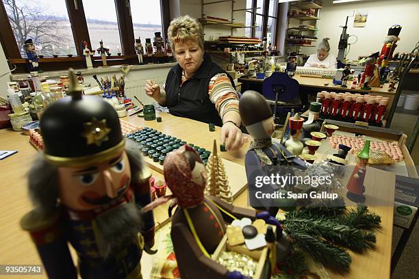 Artisan Annett Werner paints the hats and heads of wooden figurines at the Seiffener Volkskunst eG wooden toy manufactory on November 30, 2009 in...