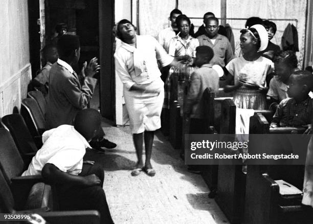 In the church aisle, a woman sways as she is overcome with religious spirit during a service at the Temple Apostolic Church, a storefront church in...