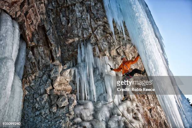 a male ice climber on a frozen waterfall - robb reece stock pictures, royalty-free photos & images