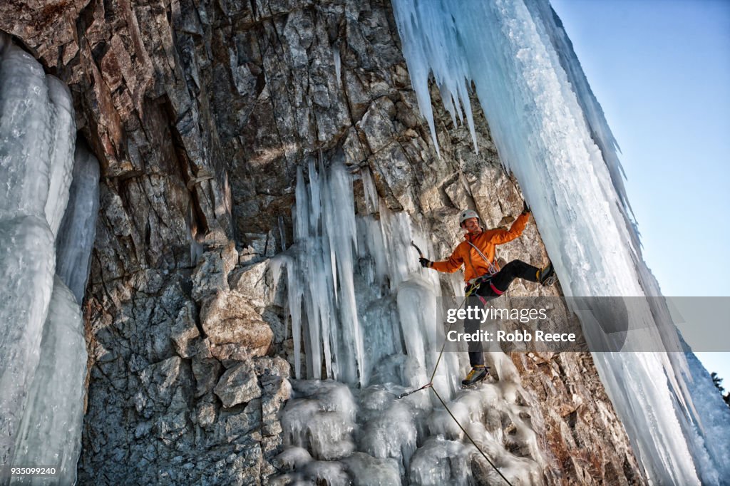 A male ice climber on a frozen waterfall