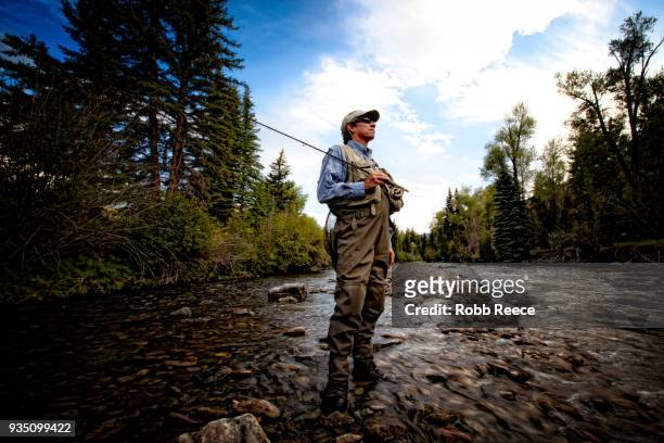 a male fly fisherman standing near a stream ready to fish - robb reece stock pictures, royalty-free photos & images