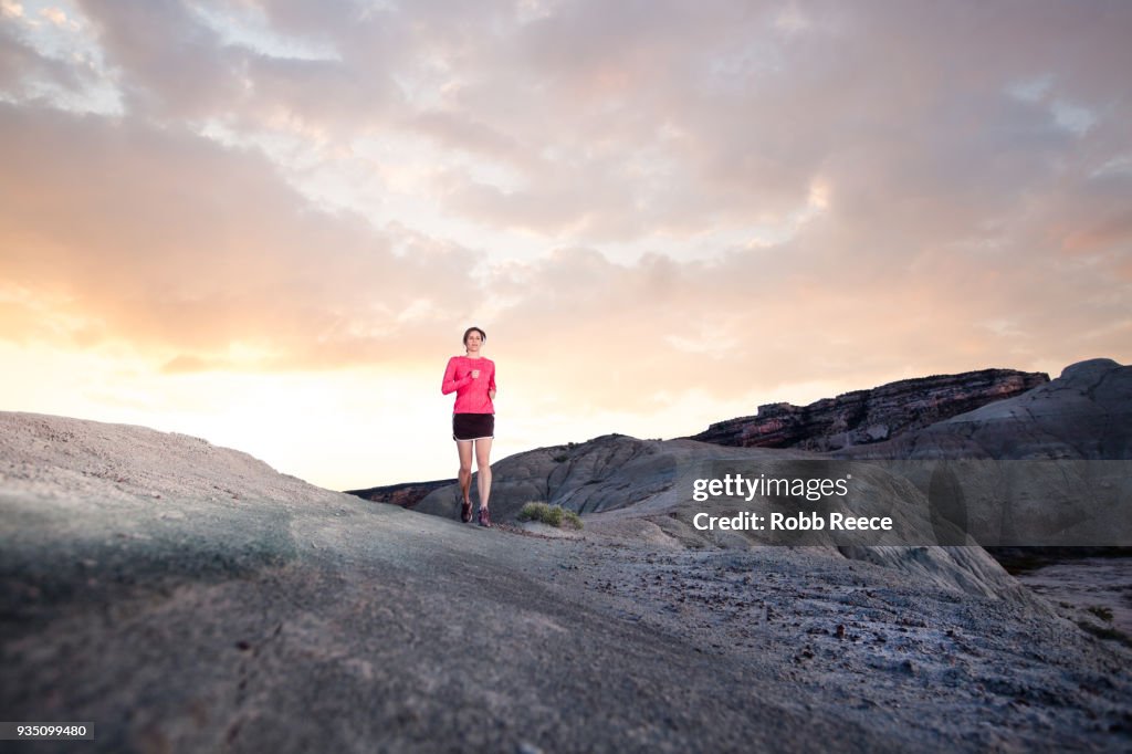 An adult woman trail running on a remote dirt trail