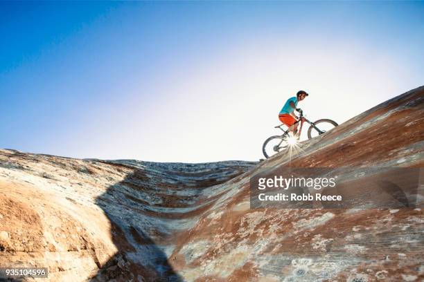 a man riding a mountain bike on an extreme sandstone ledge - robb reece stock-fotos und bilder