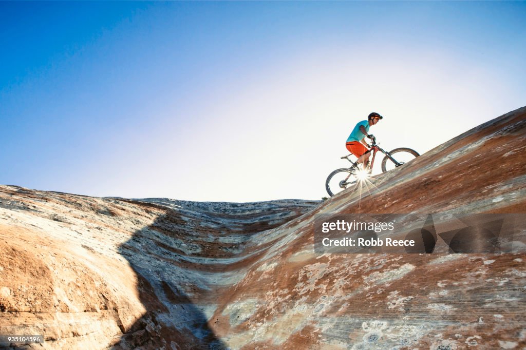 A man riding a mountain bike on an extreme sandstone ledge