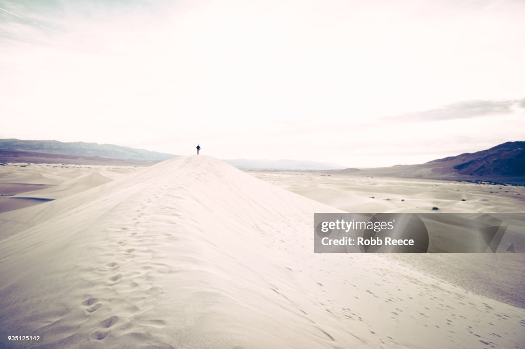 A person walking alone on a remote sand dune
