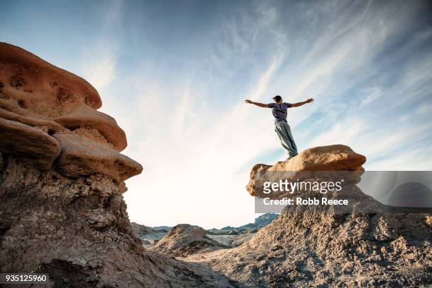 a man doing parkour on rocks in the desert - robb reece stockfoto's en -beelden