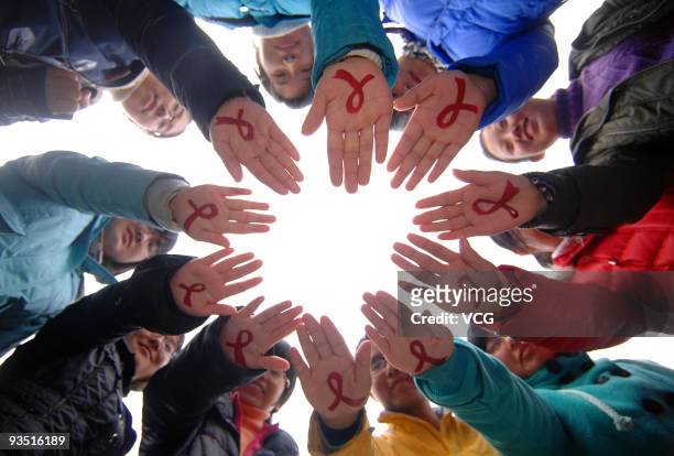 Students of Yangzhou University show the red ribbons on their hands to make World AIDS day on December 1, 2009 in Yangzhou, Jiangsu Province of...