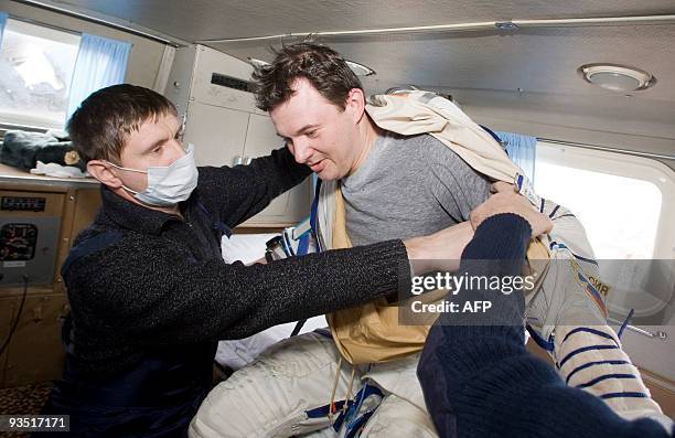 Ground crew members assist Russian cosmonaut Roman Romanenko in a vehicle after he returned to earth from the International Space Station aboard a...