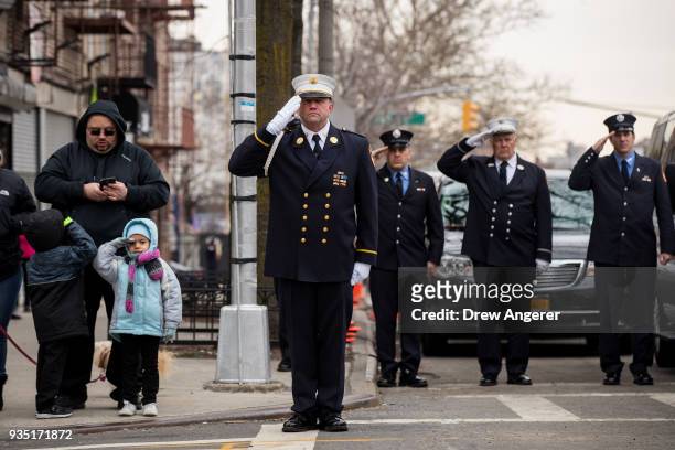 Members of the New York City fire department and young pedestrians salute as firefighter Thomas Phelan's casket is escorted into St. Michael's Church...