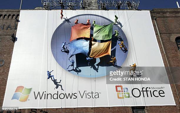 Group of performers from the Grounded Aerial Dance Theater unfurl the Microsoft logo as they hang from a seven-story tall building during the...