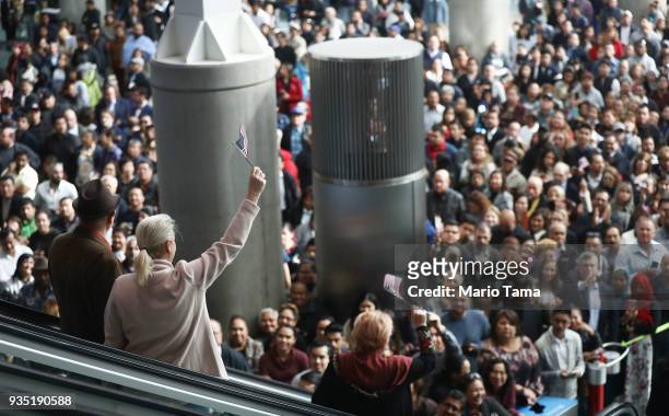 New U.S. Citizens wave American flags while departing a naturalization ceremony on March 20, 2018 in Los Angeles, California. The naturalization...