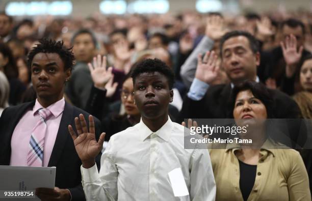 New U.S. Citizens James Maina from Kenya and Esther Ranfla from Mexico take the citizenship oath along with other new citizens at a naturalization...