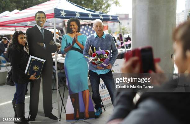 New U.S. Citizen Remigio Rivera , an immigrant from Mexico, poses with his niece Lorena Robles and a cardboard image of the Obamas following a...