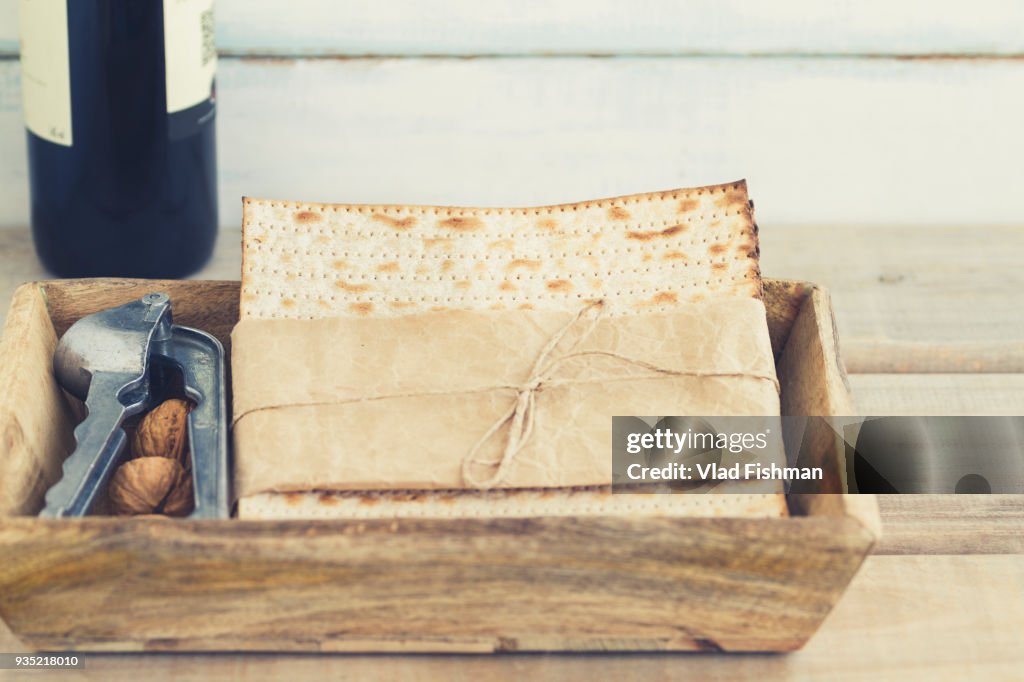 Pack of matzah or matza and Kosher red wine on a vintage wood background.Jewish Passover holiday composition with copy space and blurred background or bokeh.