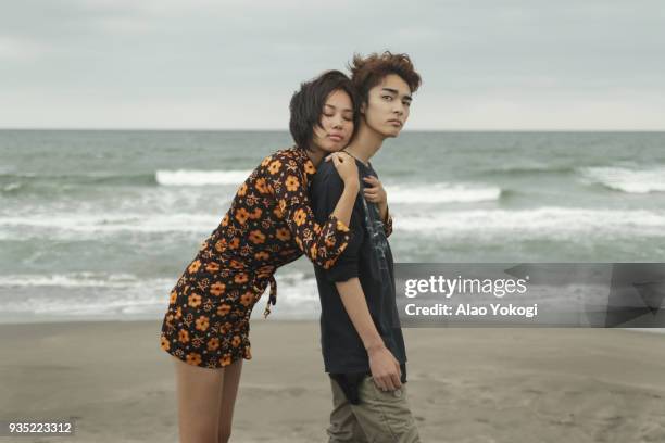 a woman and a young man are on the beach - japanese couple beach stock-fotos und bilder