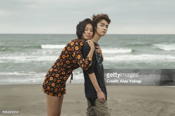 a woman and a young man are on the beach - verliefd worden stockfoto's en -beelden