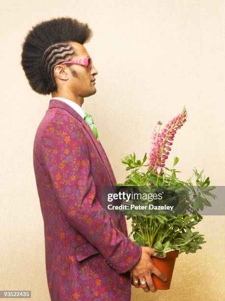 man with mohican haircut holding potted lupin. - mohican stock pictures, royalty-free photos & images