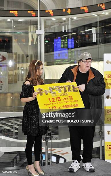 Film director Michael Moore and Japanese actress Yuko Ogura display a board which says his movie "Capitalism: A Love Story" will be screened from...