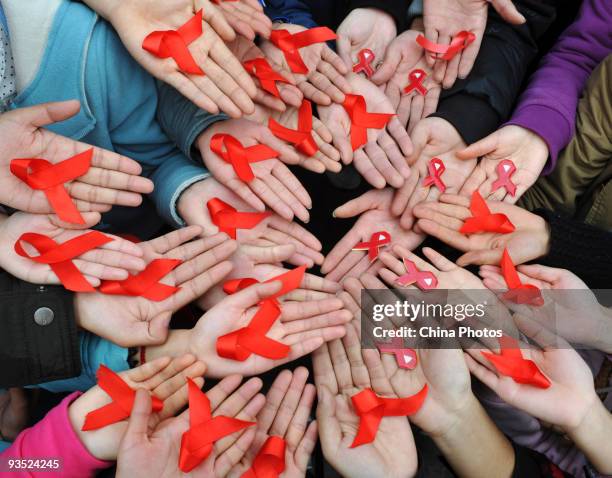 University students display red ribbons during an event to promote the awareness of Aids at the Sichuan University on the World Aids Day today,...