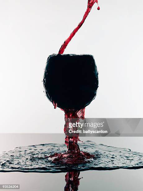 red wine pouring into overflowing glass. - overflowing glass stock-fotos und bilder
