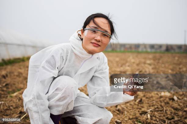 young female scientist holding test tube and soil - botaniste photos et images de collection