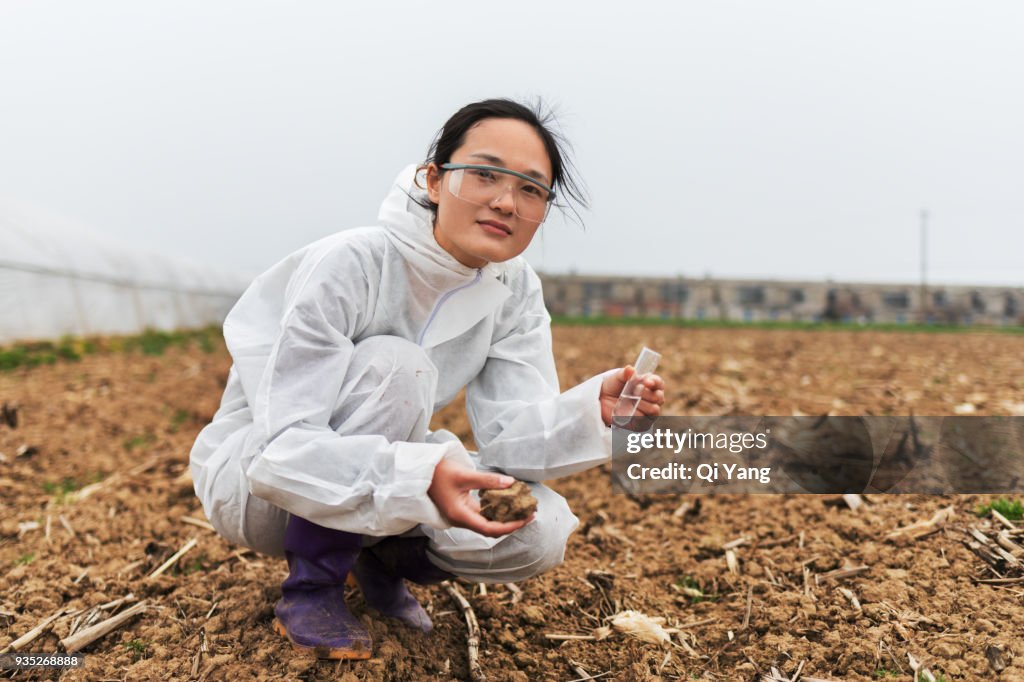 Young female scientist holding test tube and soil