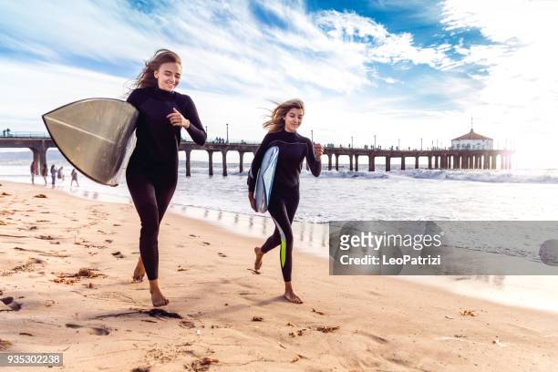 vrouwen vrienden gaan surfen in los angeles - californië - manhattan beach stockfoto's en -beelden