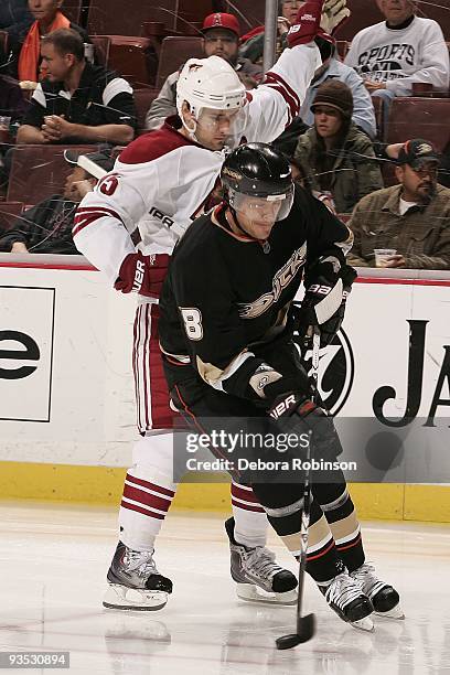 Teemu Selanne of the Anaheim Ducks handles the puck alongside the boards as Matthew Lombardi of the Phoenix Coyotes defends from behind during the...