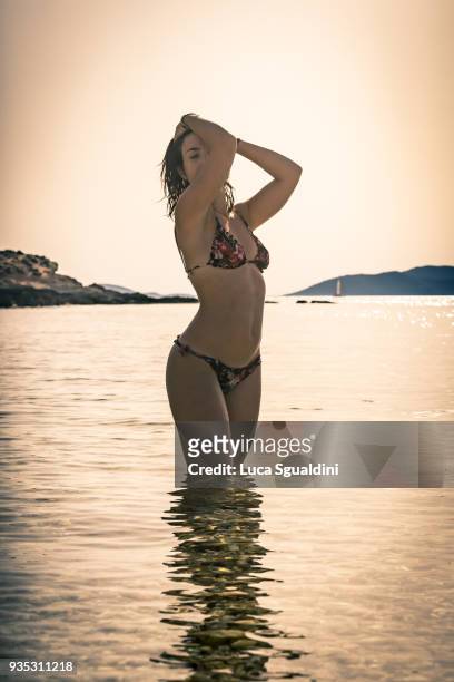 young woman enjoying the late afternoon sun, in the warm waters of sardinia. - controluce stock pictures, royalty-free photos & images