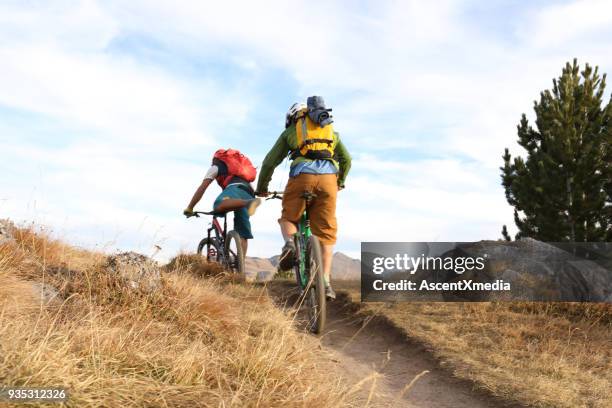 two men cycle along ridge on trail - uphill stock pictures, royalty-free photos & images