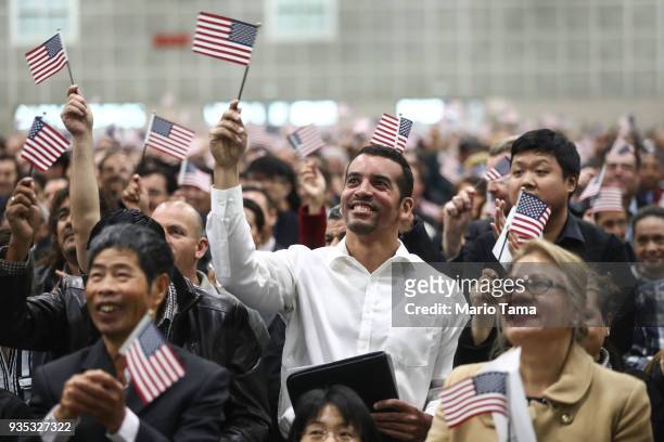New U.S. Citizens wave American flags at a naturalization ceremony on March 20, 2018 in Los Angeles, California. The naturalization ceremony welcomed...