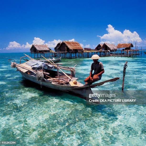 Fisherman in a pirogue with stilt structures in the background, Tawi-Tawi island, Philippines.