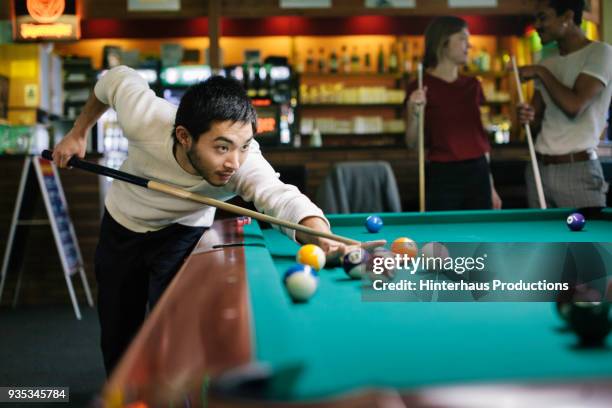 young man playing pool with friends - billiard ball game stock pictures, royalty-free photos & images