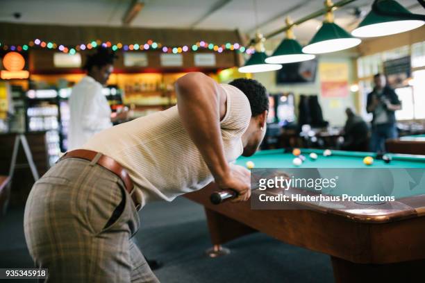 stylish young man taking shot during pool game - billard tisch stock-fotos und bilder