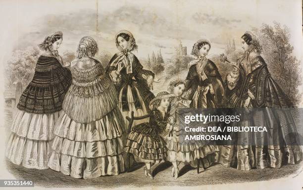 Young women wearing a dresses with flounced skirts and lace fringed capes, two little girls wearing flounced skirts in the centre, illustration by...