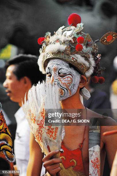 Man with painted mask and traditional hat during Taoist ceremony at the Matsu Temple, County Chiayi, Taiwan.
