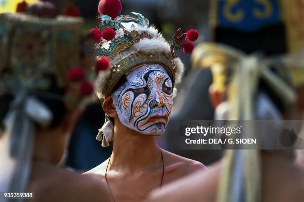 Man with painted mask and traditional hat during Taoist ceremony at the Matsu Temple, County Chiayi, Taiwan.