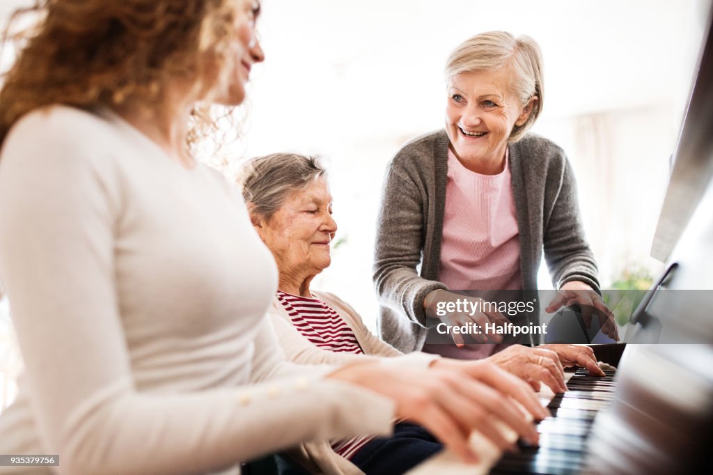 A girl with mother and grandmother playing the piano.