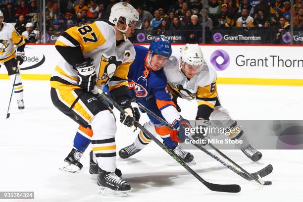 Brock Nelson of the New York Islanders battles for the puck against Sidney Crosby and Jamie Oleksiak of the Pittsburgh Penguins at Barclays Center on...