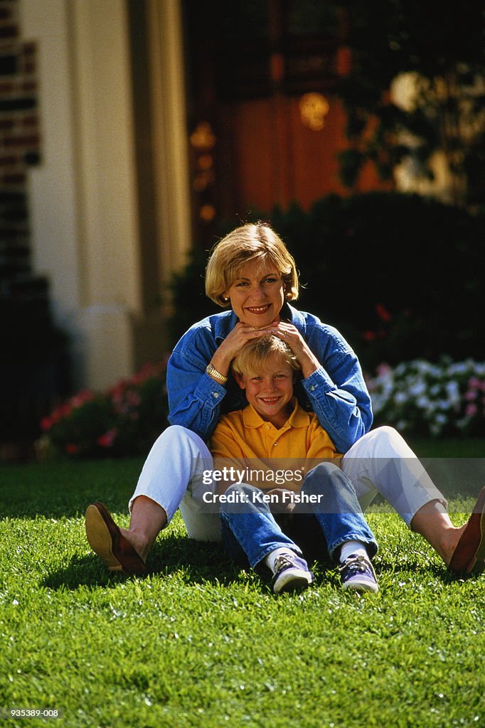 Mother and son(8-10)sitting on front lawn
