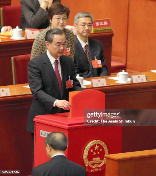 State Councilor Wang Yi votes during the seventh plenary session of the 13th National People's Congress at the Great Hall of the People on March 19,...