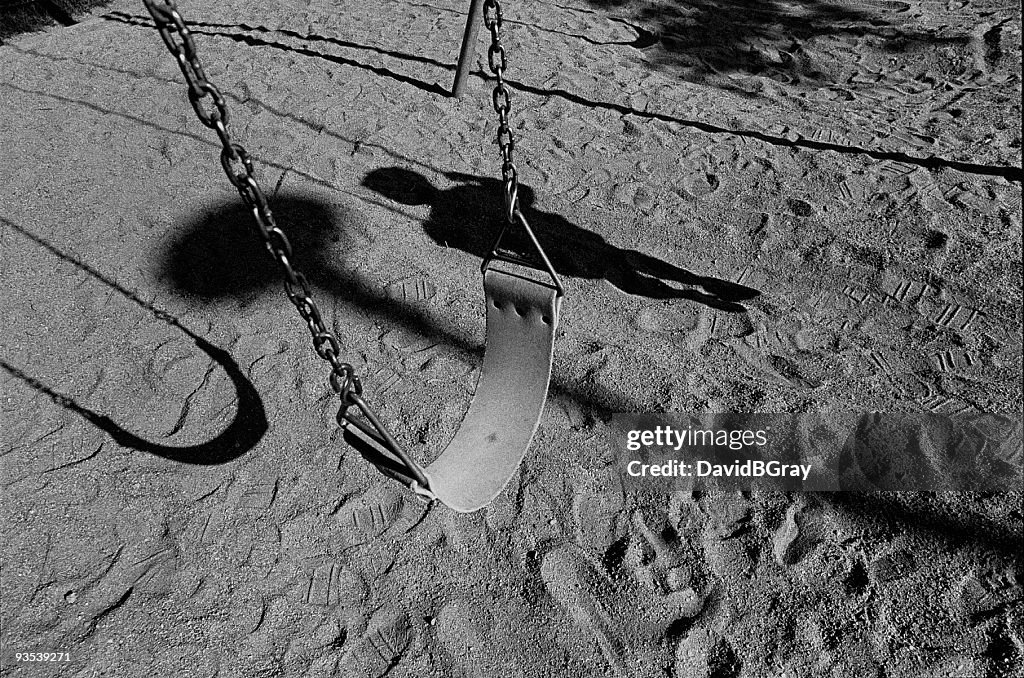 Childhood memories : empty swing with child's shadow