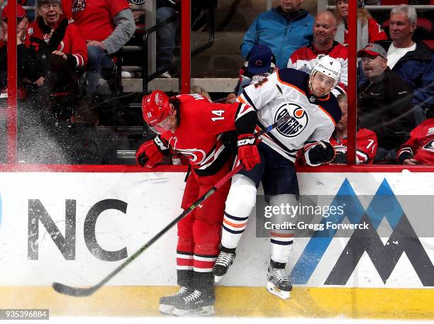 Justin Williams of the Carolina Hurricanes and Kris Russell of the Edmonton Oilers collide along the boards during an NHL game on March 20, 2018 at...