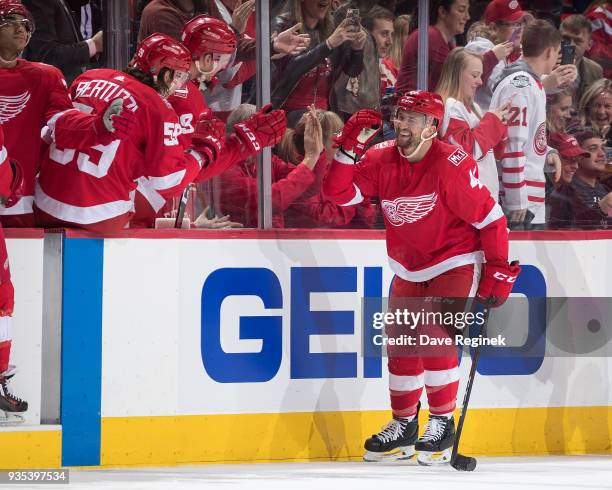 Luke Glendening of the Detroit Red Wings pounds gloves with teammates on the bench following his second period goal during an NHL game against the...