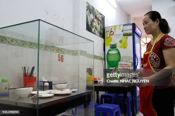 In this photograph taken on March 20 a waitress carries dishes to customers next to the glass-encased table where former US President Barack Obama...