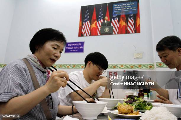 In this photograph taken on March 20 customers enjoy a meal at Bun Cha Huong Lien restaurant, now dubbed "bun cha Obama" with a photograph of former...