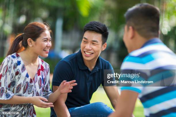 freunde im chat im park - filipino ethnicity stock-fotos und bilder