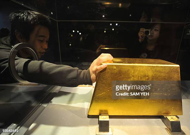 An visitor touches the world's largest solid gold brick weighing 220kg, at the Jinguashi Gold Museum in Ruifang, Taipei county, on December 2, 2009....