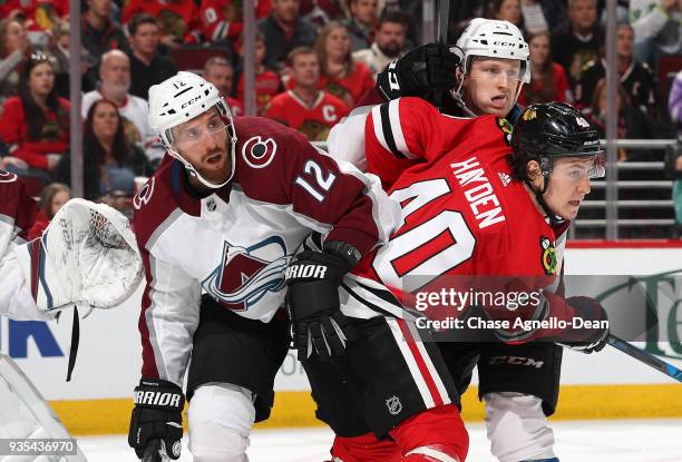 John Hayden of the Chicago Blackhawks battles for position against Patrik Nemeth and Nathan MacKinnon of the Colorado Avalanche in the second period...