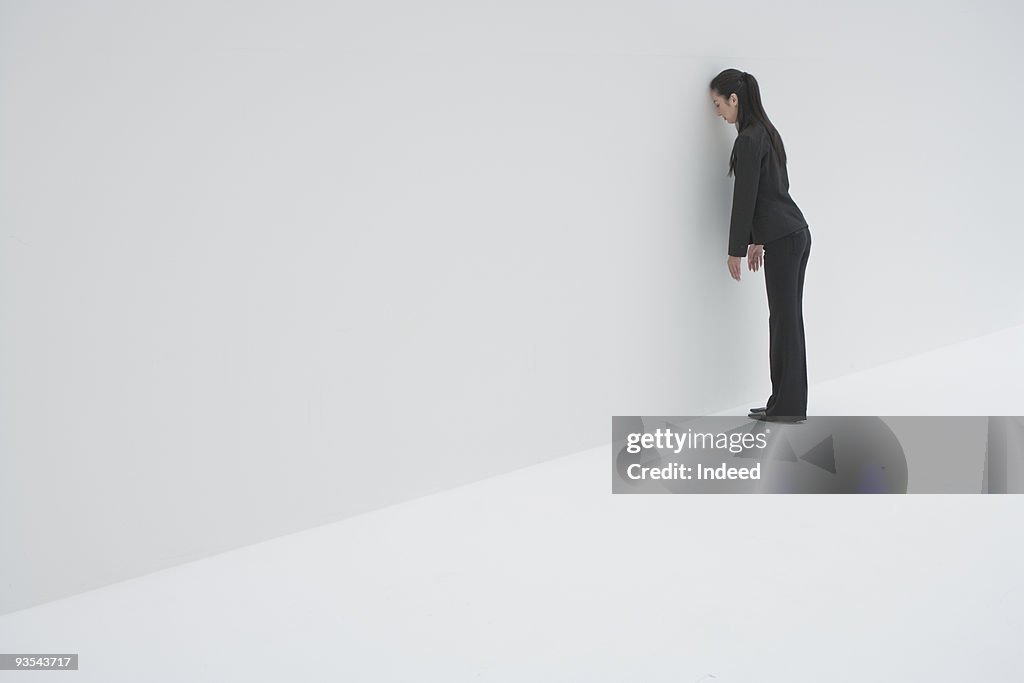 Businesswoman leaning head against the wall